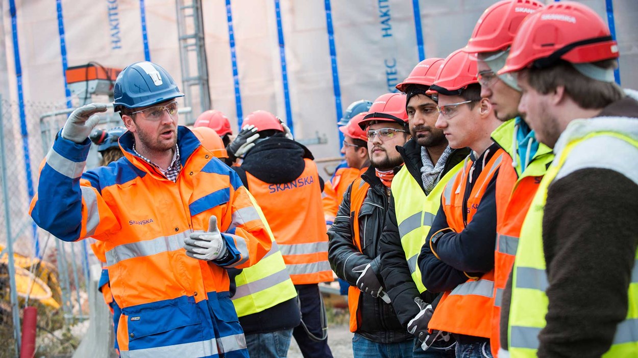 ungdommer på byggeplass sammen med en mannlig ansatt fra Skanska