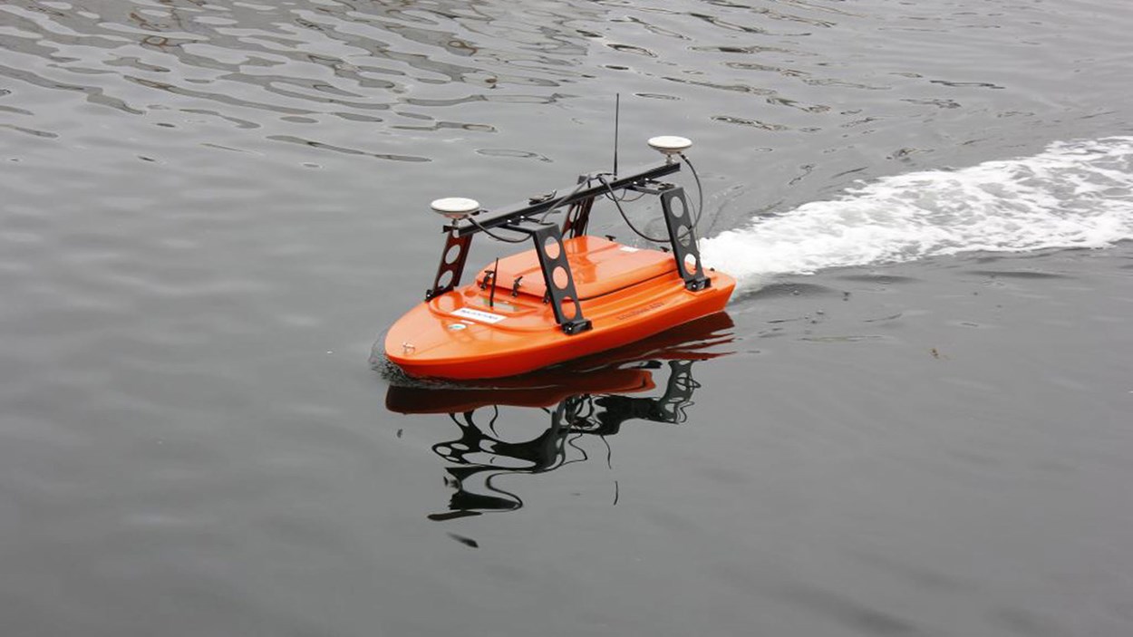 Liten fjernstyrt oransje båt på vann