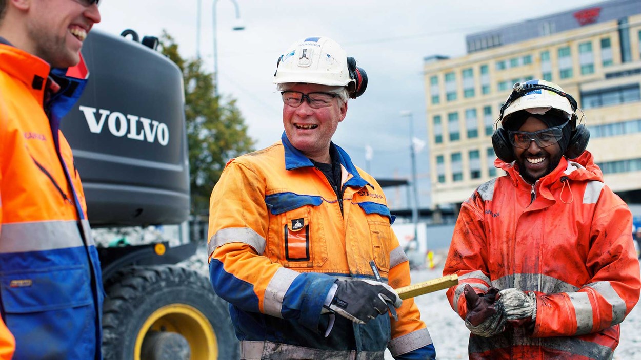 Tre mannlige, blide fagarbeidere på job på byggeplass Oslo