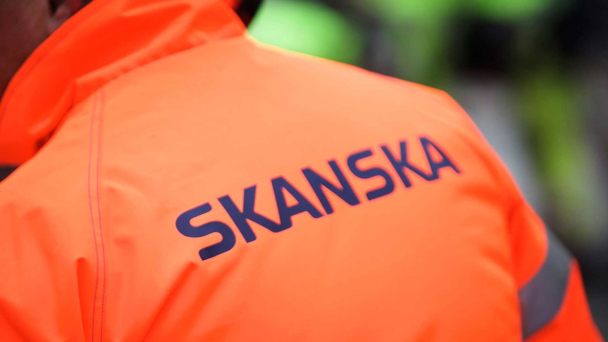 Skanska logoen plassert på ryggen på en oransje jakke