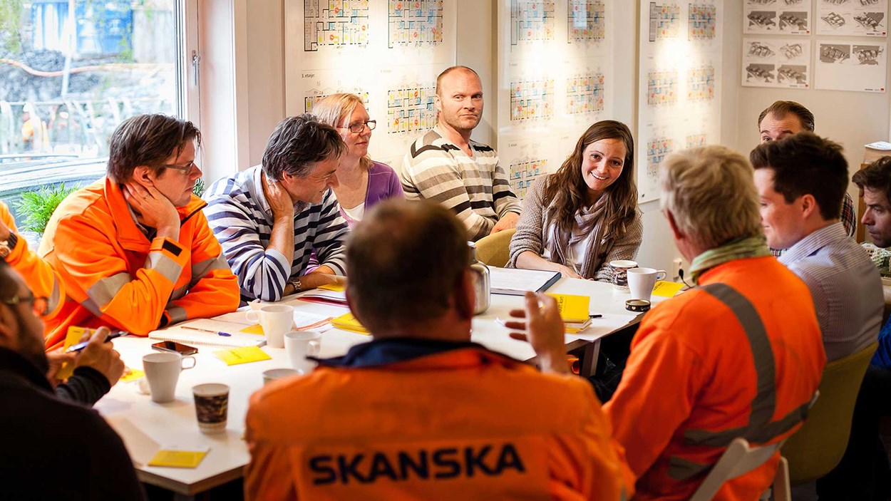 En samling av men og kvinner sittende rundt et bord i en positiv samtale med hverandre