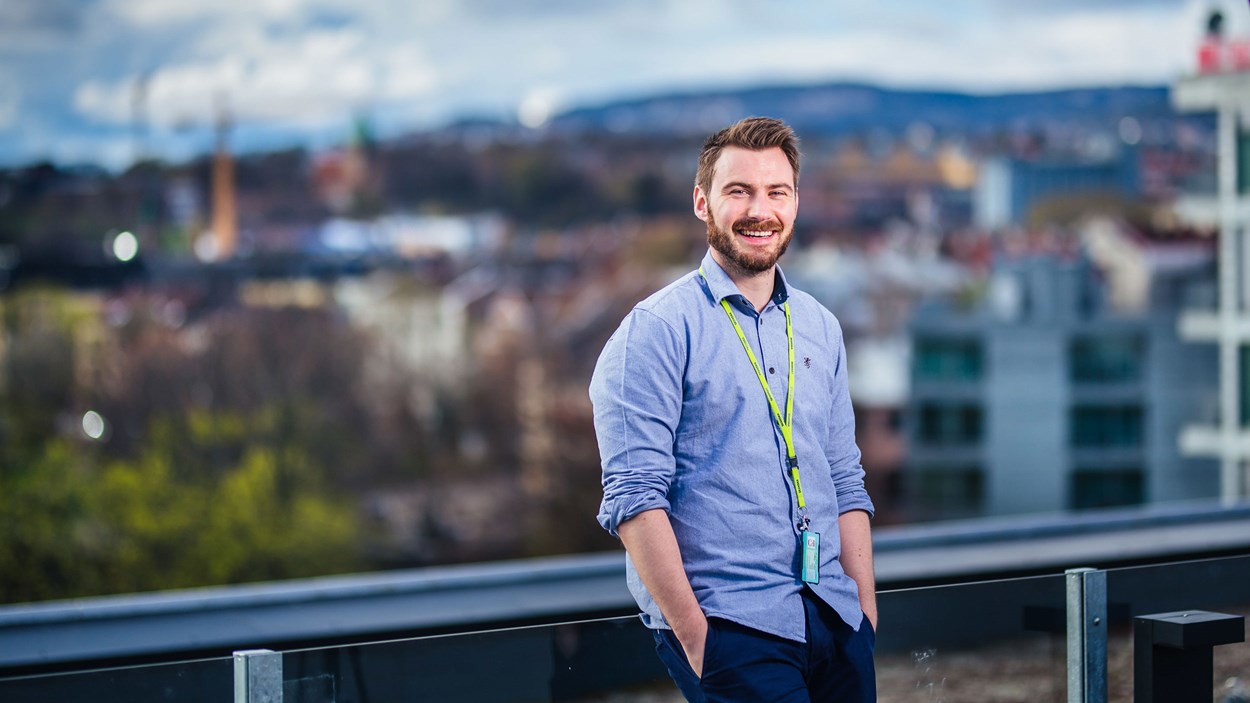 Blid ung mann stående på en takterrasse