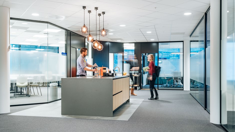 En gutt og en jente stående ved kaffemaskin utenfor flere møterom